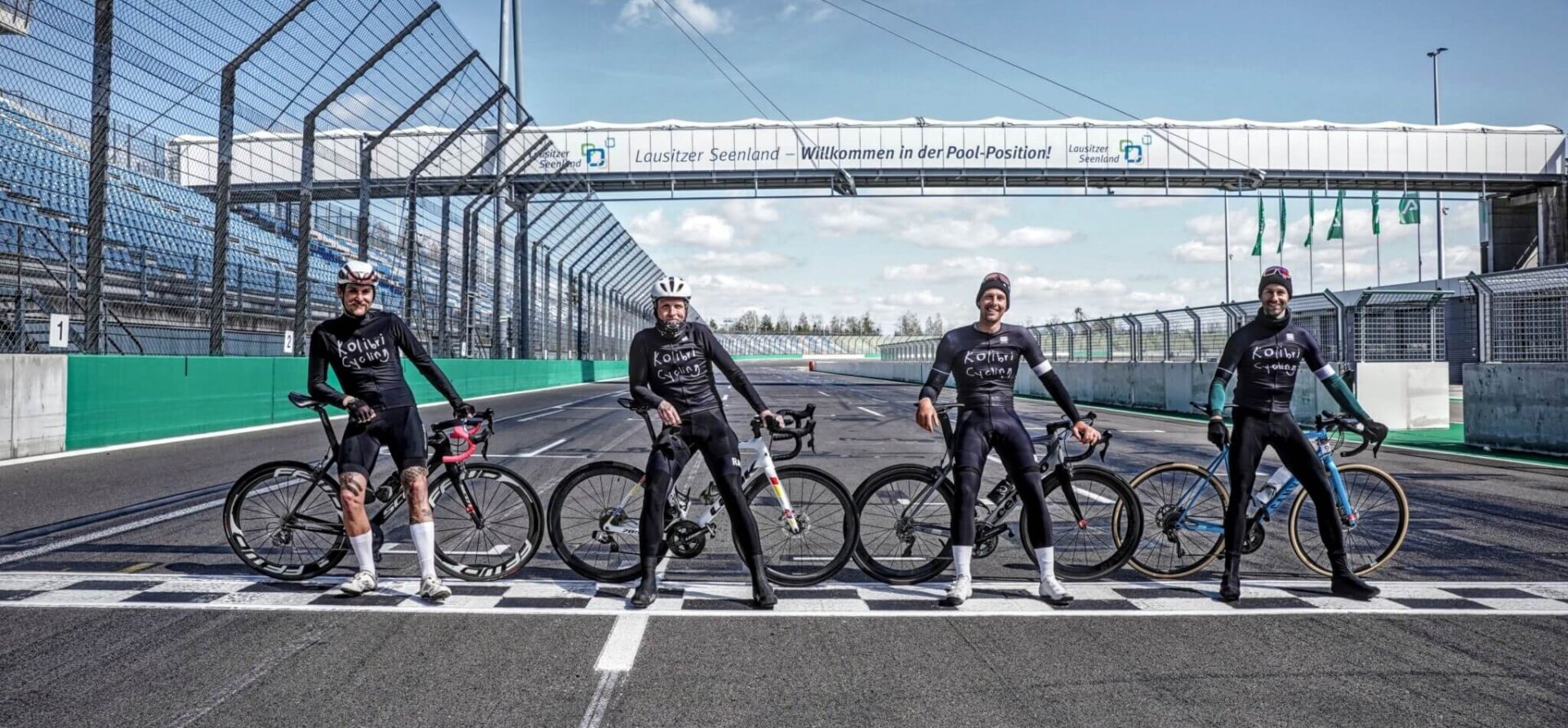 Rennradfahrer beim Gruppenfoto auf der Start-Ziel-Geraden des DEKRA Lausitzrings während des VELOFONDO Bike Festivals