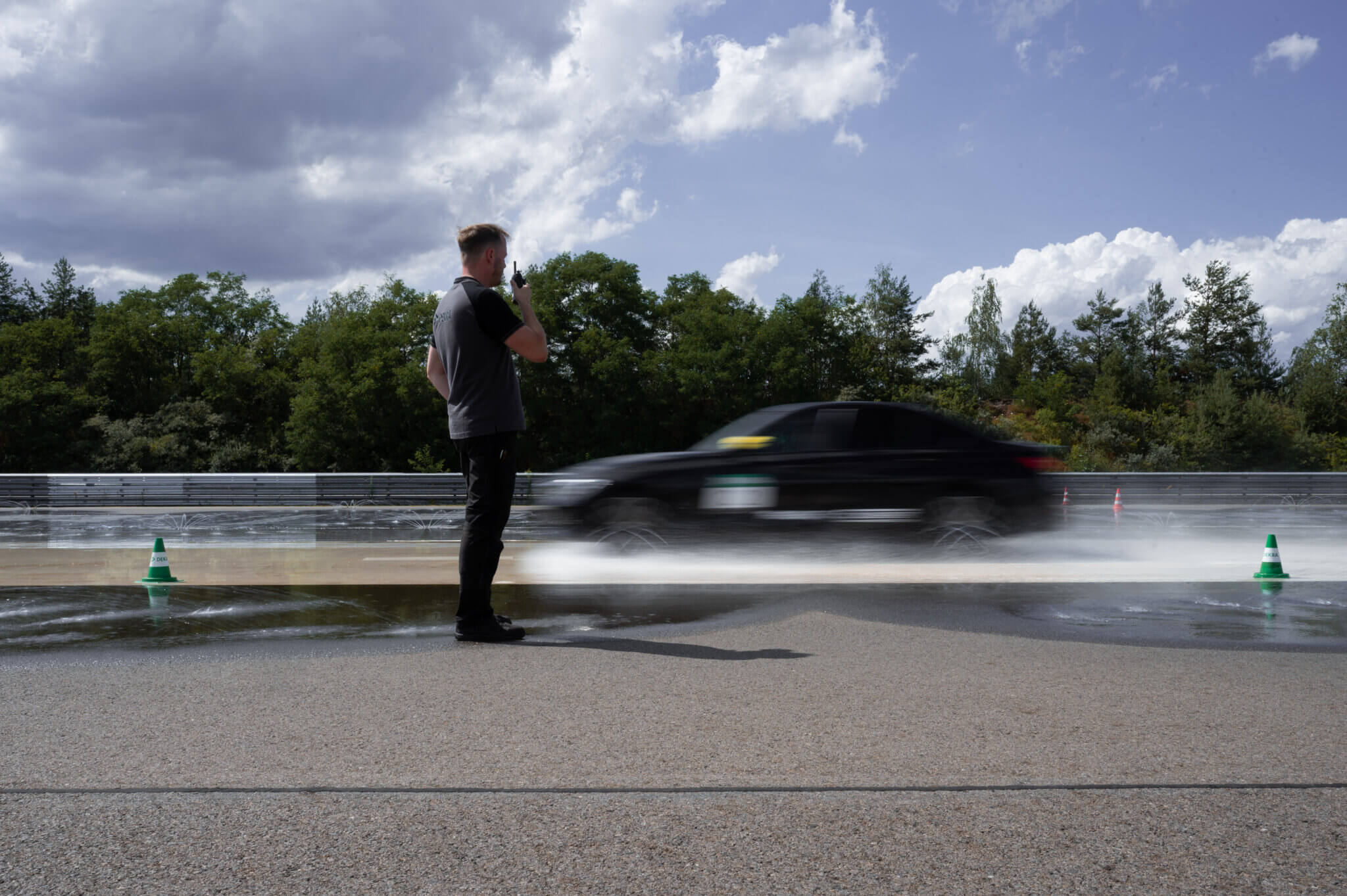 Trainer beobachtet Fahrzeug beim Fahrsicherheitstraining auf dem DEKRA Lausitzring bei Brems- und Ausweichübungen auf nasser Fahrbahn